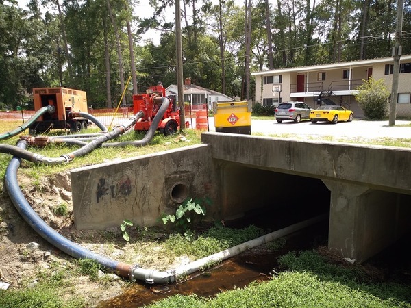 [Pipe under bridge by apartments]